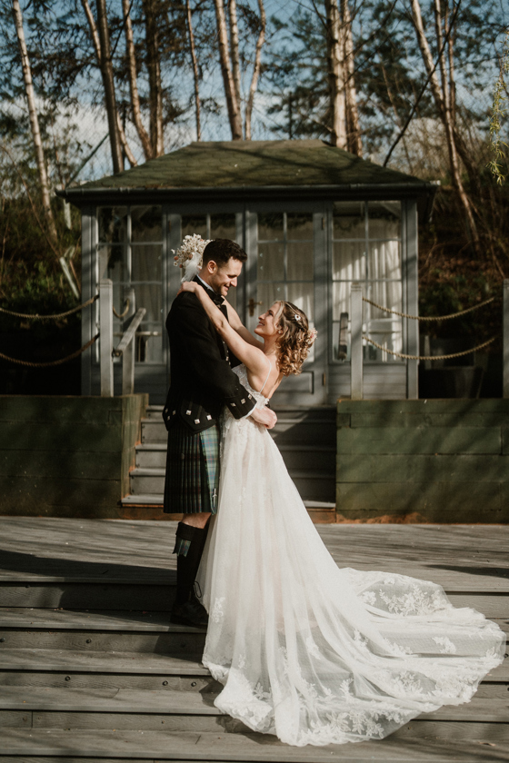 Portrait image of a bride and groom embracing on stairs at The Venue, Eskmills